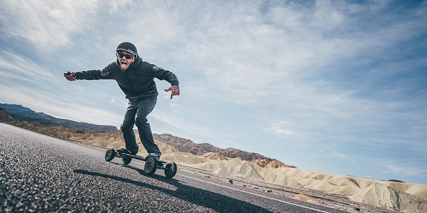 Mann fährt auf elektronischem Longoard auf straße