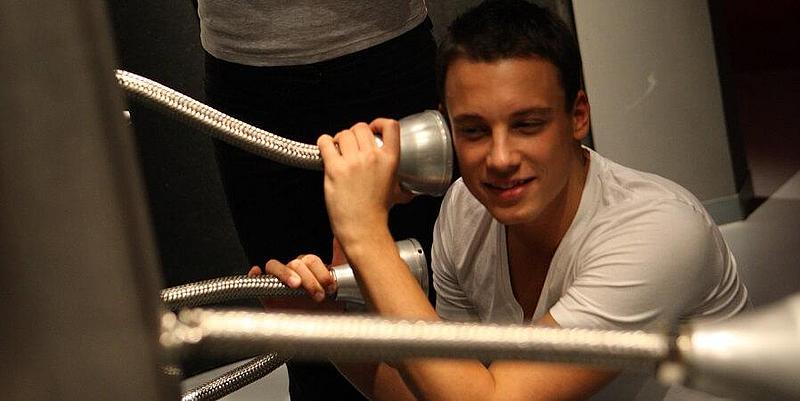 zwei Jugendliche die durch eine Art Lautsprecherrohr verschiedene Klänge hören