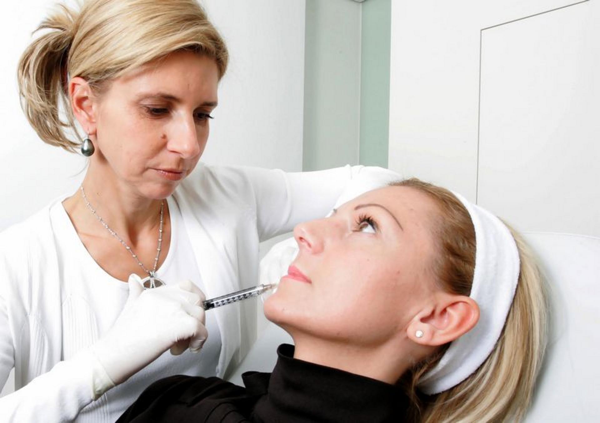 Ärztin mit Spritze im Gesicht von Patientin