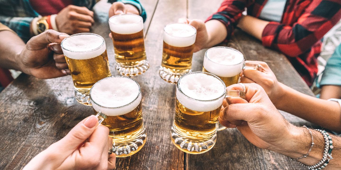 Mehrere Menschen die ein Krügerl Bier in die Luft halten