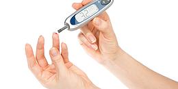 Diabetiker misst Blutzuckerwerte mittels Nadel und Teststreifen über Blut das aus dem Finger tropft.
