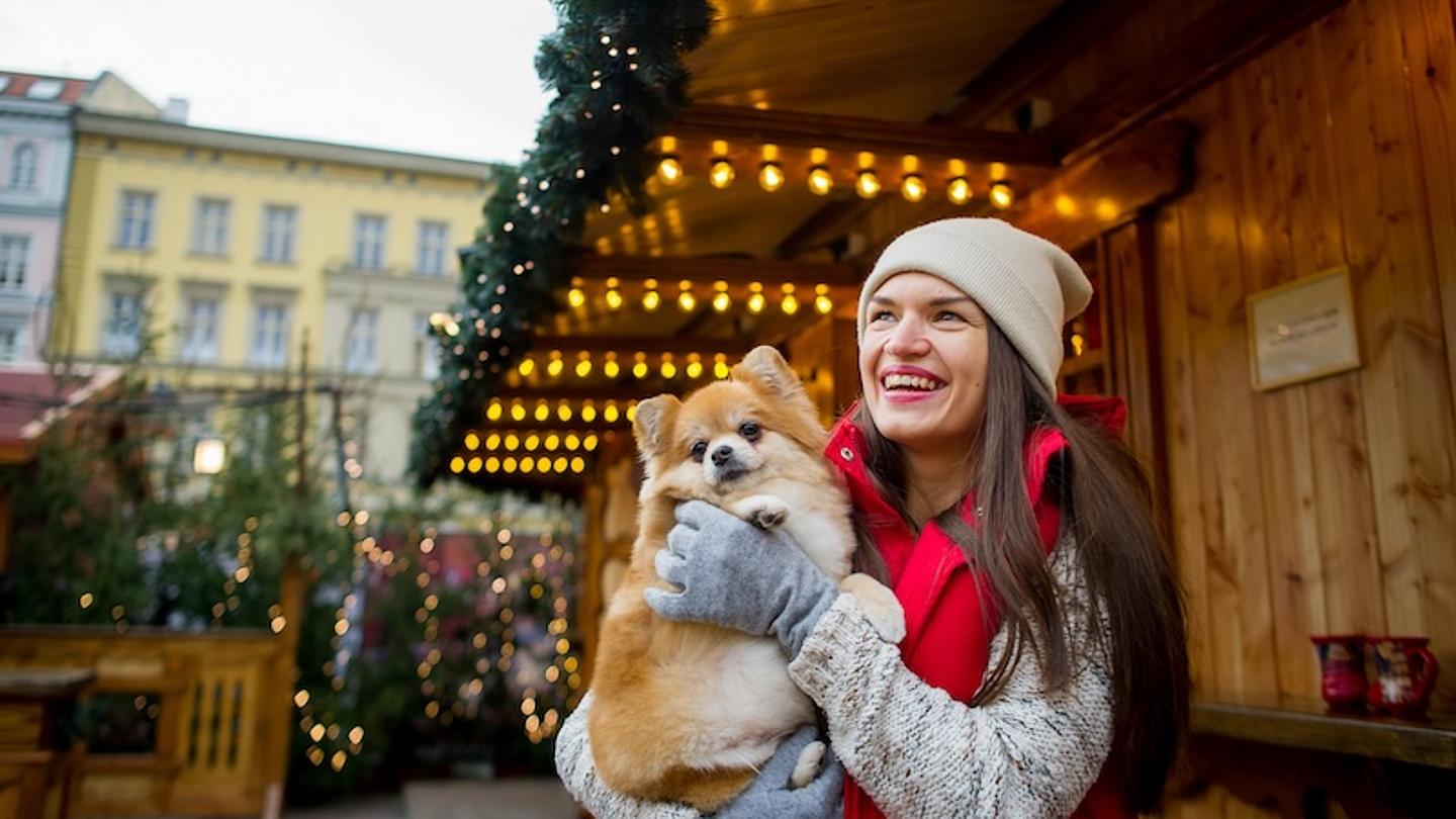 Frau mit Hund im Arm auf Weihnachtsmarkt