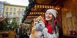 Frau mit Hund im Arm auf Weihnachtsmarkt