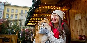 Frau mit Hund im Arm auf Weihnachtsmarkt