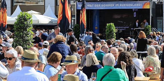 Festbänke und Schirme, viele Menschen, eine Bühne Am Hof in Wien