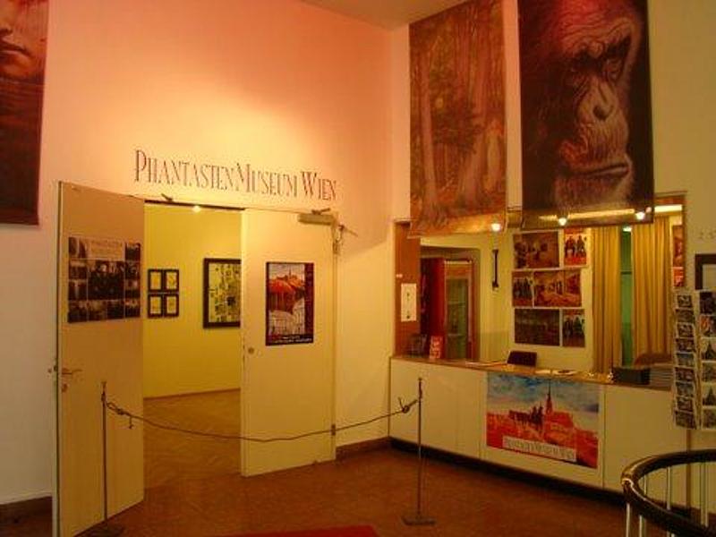 Raum des Museums mit vielen Gemälden und der Eingangstür zu weiteren Räumen
