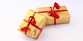 Zwei golden eingepackte Geschenke mit roten Schleifen