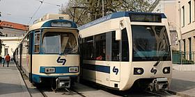 Alter und neuer Niederflur Zug der Badner Bahn neben einander auf den Schienen