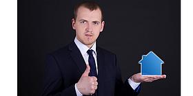 Mann hält Haus in einer Hand und zeigt thumbs up