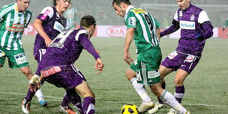 Wiener Derby Spieler in violetten und in grünweißen Trikots kämpfen um den Ball