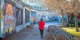 joggerin von hinter am wiener donaukanal mit graffitti Wand links