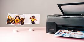 drucker mit fertigem Ausdruck im Fach, daneben 2 Fotos am Ständer