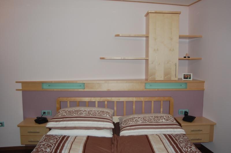 Schlafzimmereinrichtung aus hellem Holz mit Kopfteil, Nachtkästchen, Wandregale
