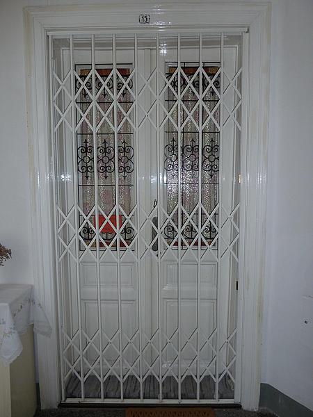 Weißes Scherengitter vor einer Wiener Altbauwohnung Eingang
