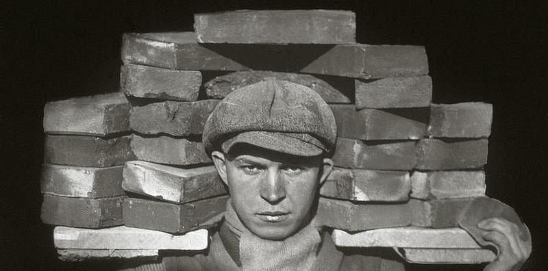 Mann mit Ziegelsteinen auf der Schulter