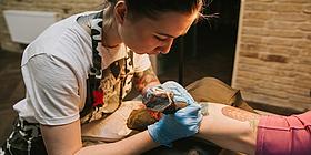 Junge Frau beim Tätowieren eines Unterarms