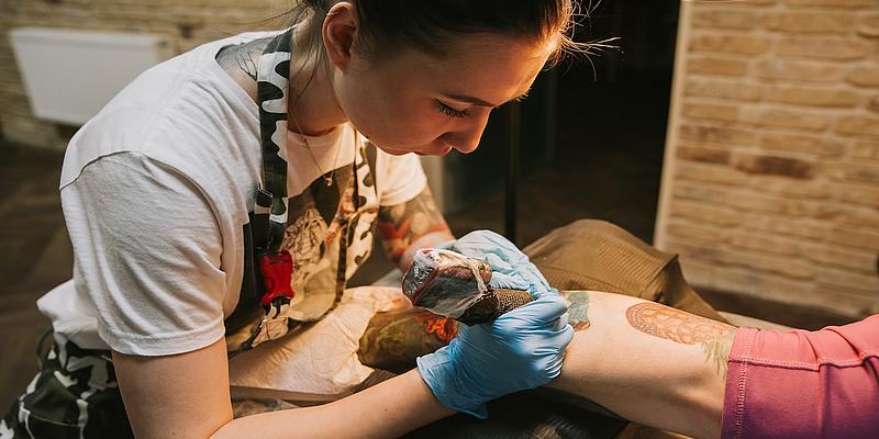 Junge Frau beim Tätowieren eines Unterarms