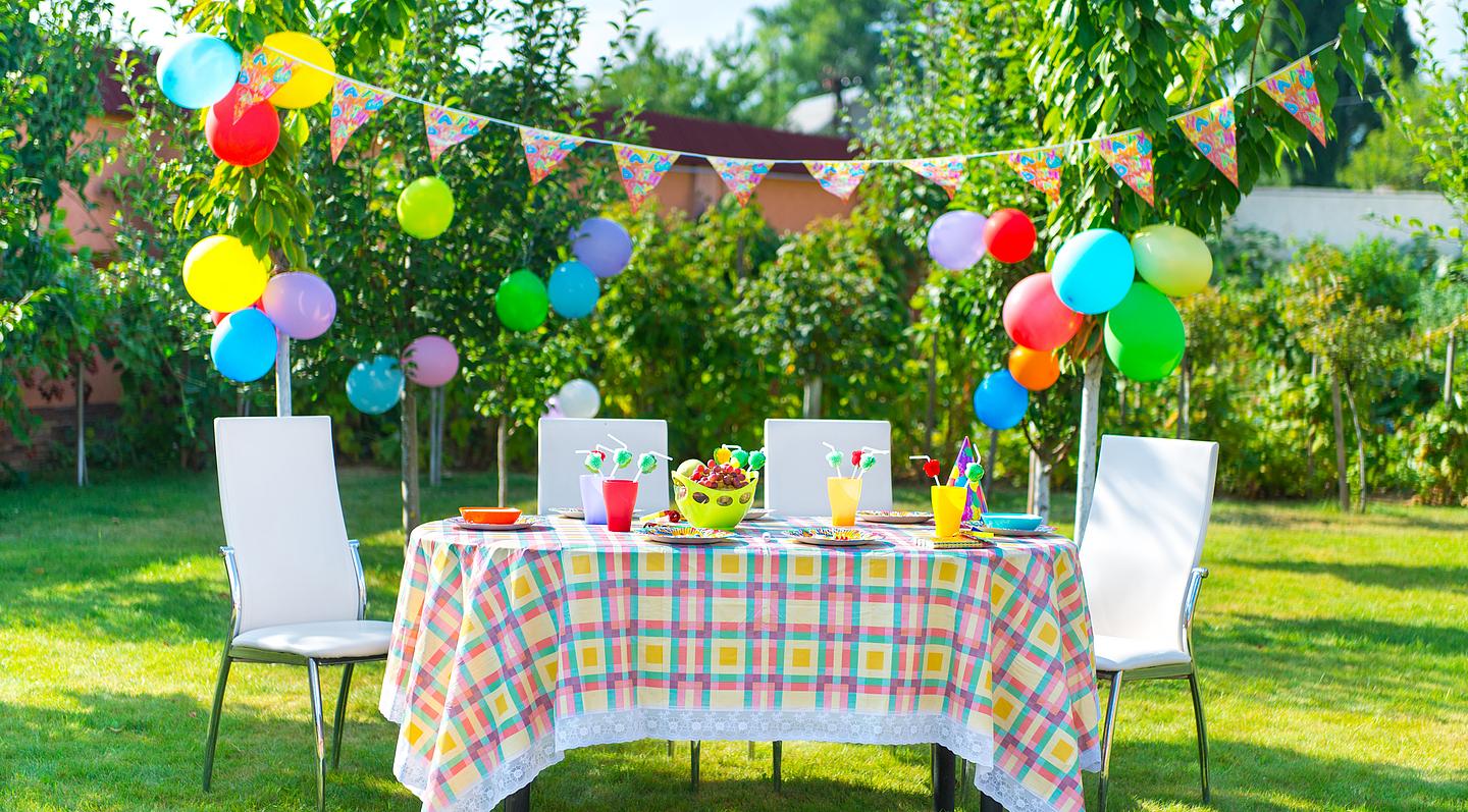 Ein Tisch im Freien mit bunter Dekoration und Luftballons