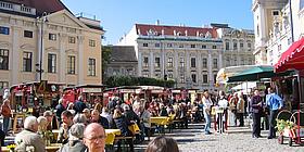 Menschen auf Sitzbänken auf einem Straßenmarkt