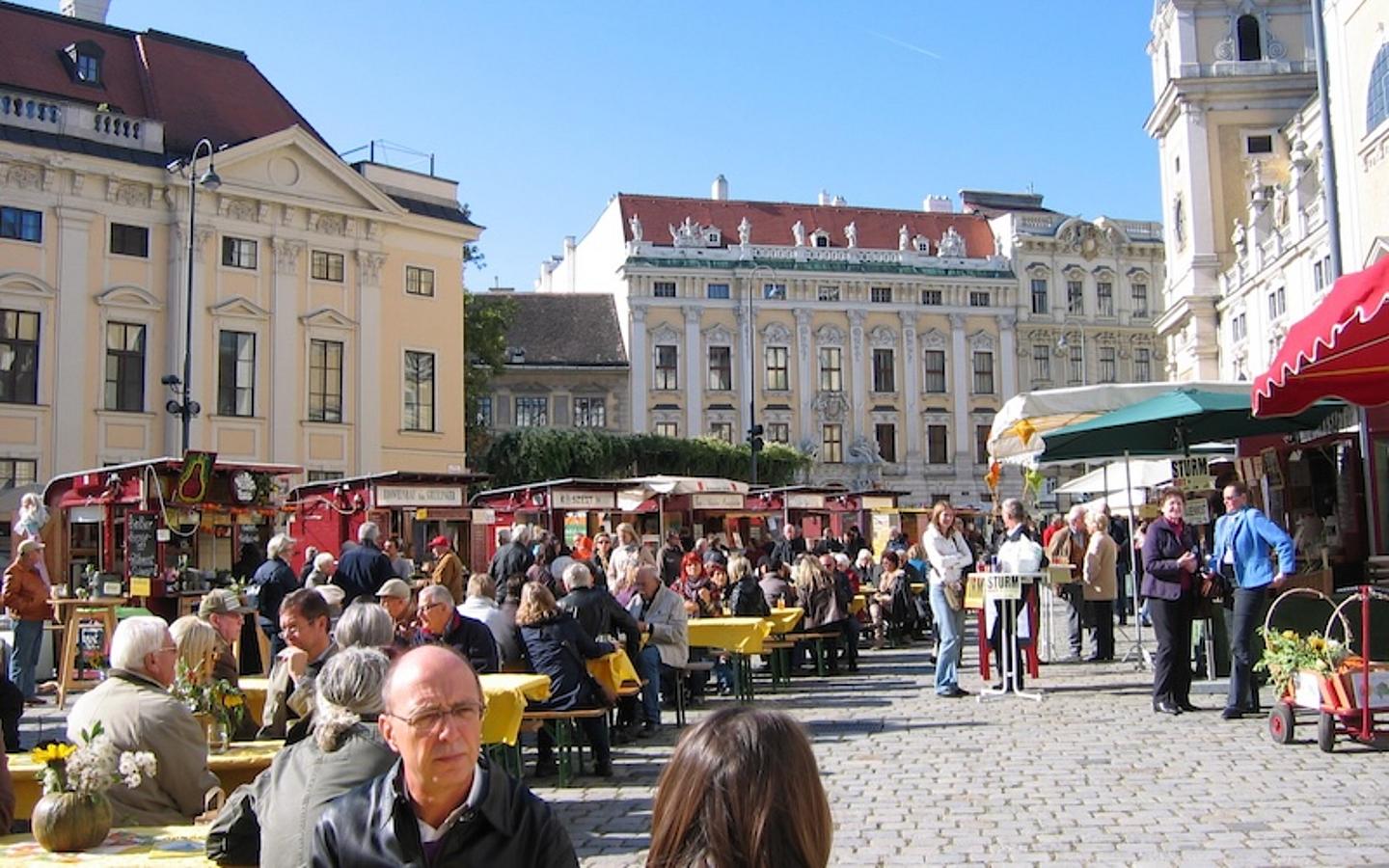 Menschen auf Sitzbänken auf einem Straßenmarkt