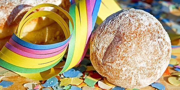 Krapfen auf dem Tisch mit Konfetti und Luftschlangen