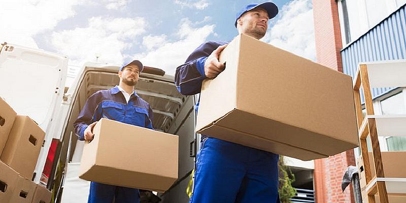 zwei blaumänner tragen Couch, Kartons vor LKW