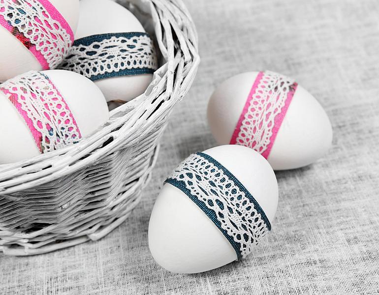 Weiße Ostereier mit buntem Band und Spitze in der Mitte umwickelt
