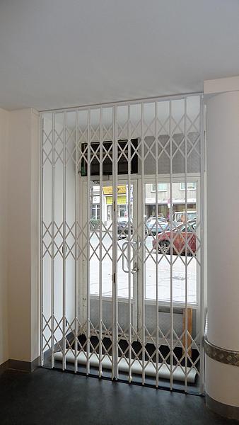 Weißes Scherengitter geschlossen vor Tür
