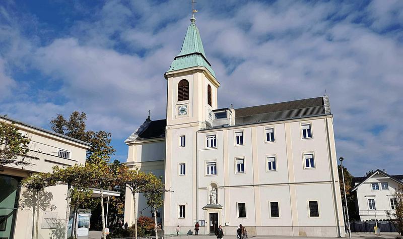 Eine weiße Kirche steht auf einem asphaltierten Platz.
