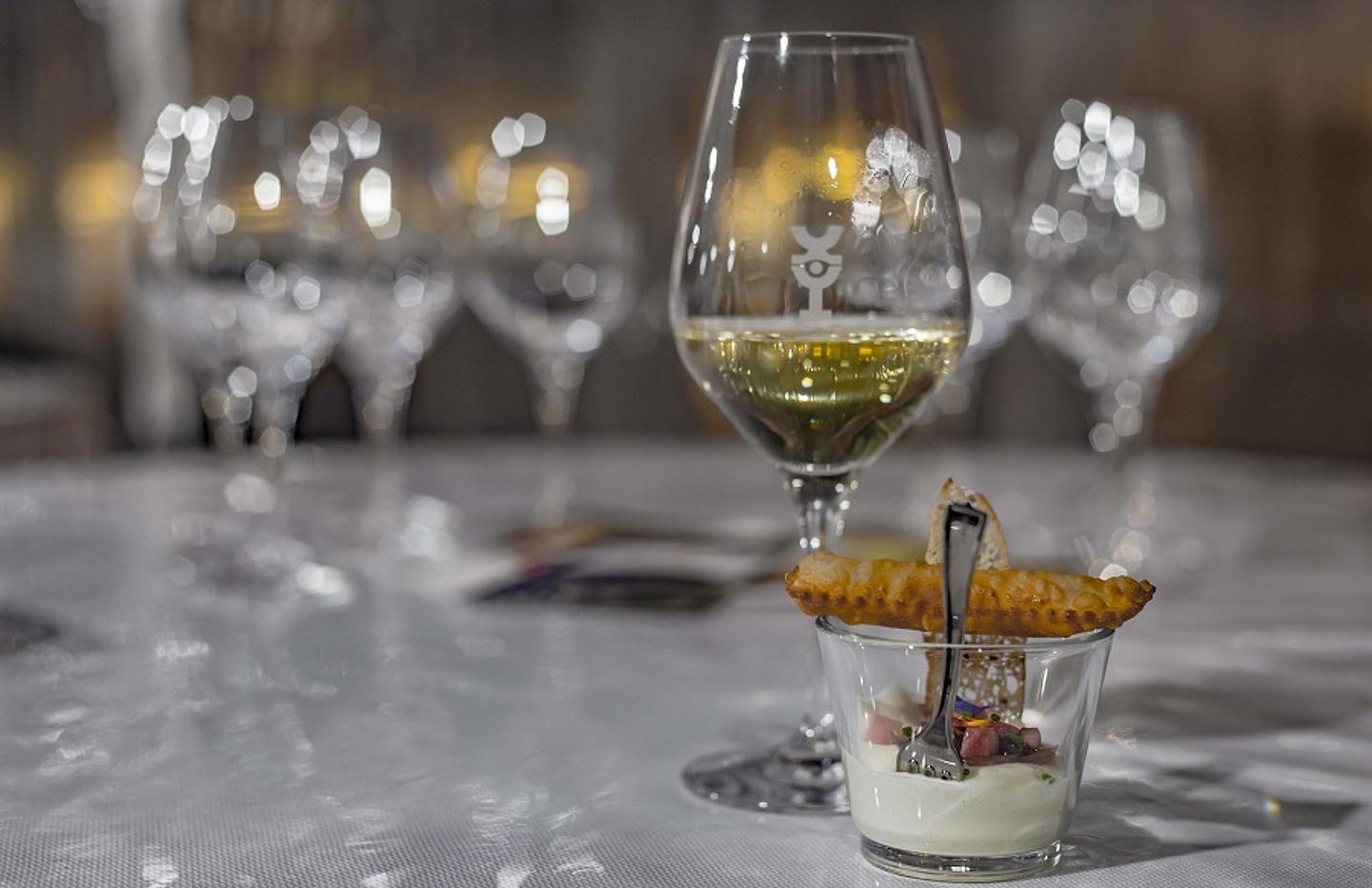 Ein Desertglas mit einem Weißwein dahinter