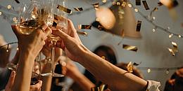 Personengruppe, die mit Gläsern anstößt, Konfetti