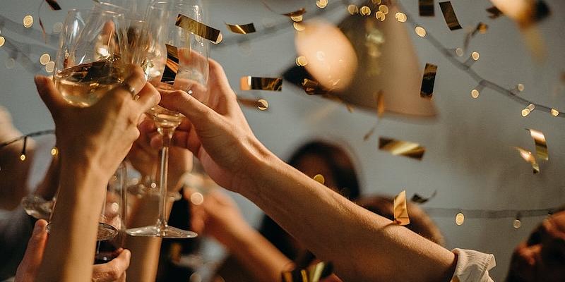 Personengruppe, die mit Gläsern anstößt, Konfetti