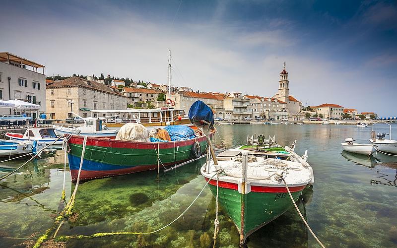 Bunte Boote im Vordergrund mit Blick auf kroatische Küstenstadt