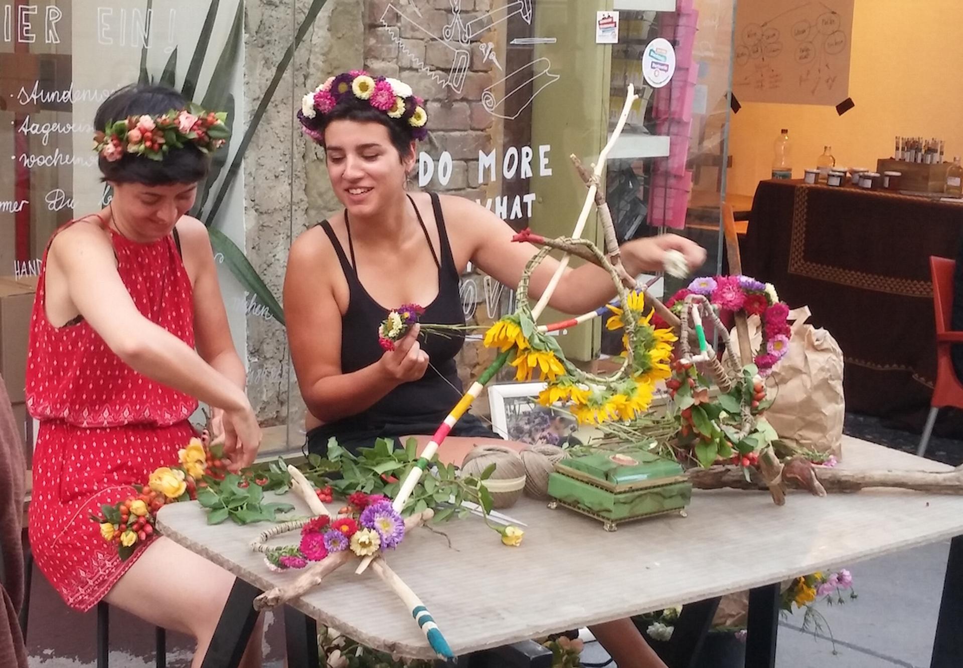 zwei Frauen binden Blumengränze