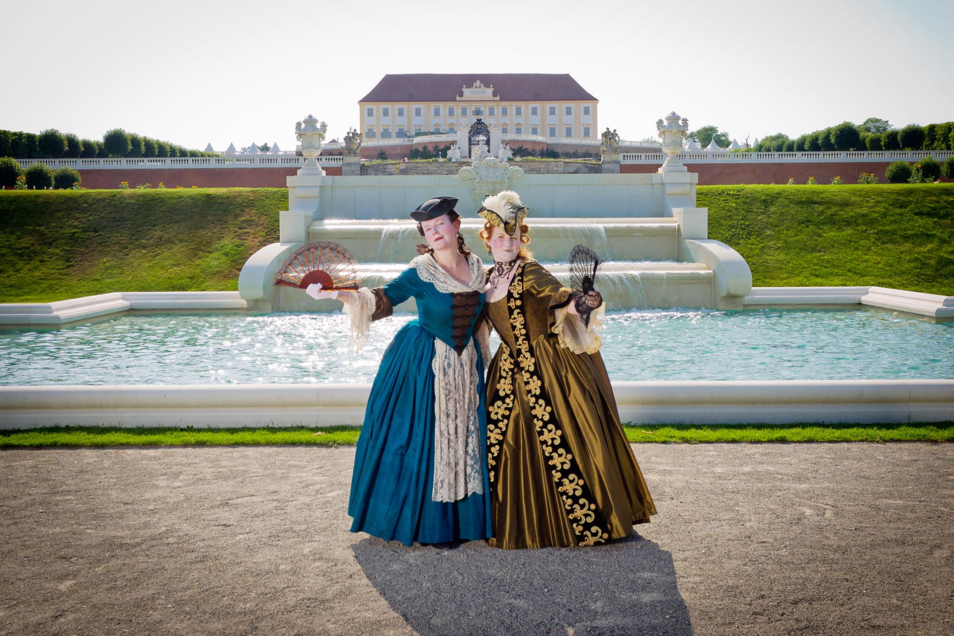 Zwei Frauen im Barockkostüm vor der Kleinen Kaskade auf der siebten Terrasse von Schlosshof