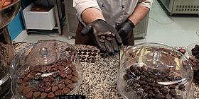 Schokomuseum hand die Schokodrops hält, viel Schokolade im Hintergrund