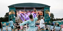 Frau tanzend von hinten, im Hintergrund eine der Wiener Kultursommer-Bühnen