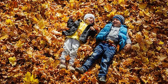 Kids genießen die Herbstferien und spielen im Laub