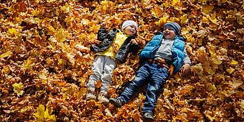 Kids genießen die Herbstferien und spielen im Laub
