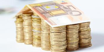 kleines Haus das aus Geld gebaut ist, gestapelte Münzen und ein 50-Euro-Dach