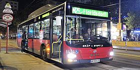 Bild von der Nightline N29 in Richtung Floridsdorf bei der Station Schwedenplatz. Zwei Personen steigen gerade zu. Im Hintergrund leuchten die Imbisbuden.