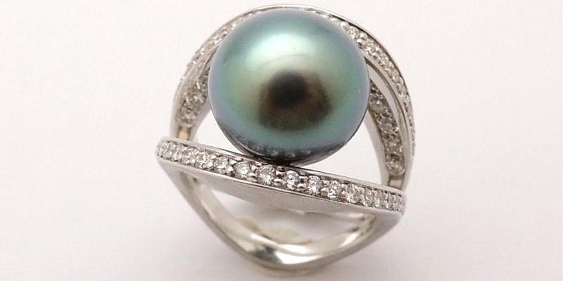 Ring mit 2 Diamantbesetzten Stegen in der Mitte eine grünlich schimmernde Süßwasserperle