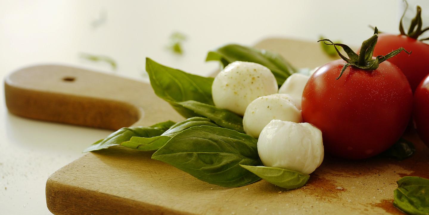 Tomaten, Mozzarella und Basilikum auf einem hölzernen Brett 