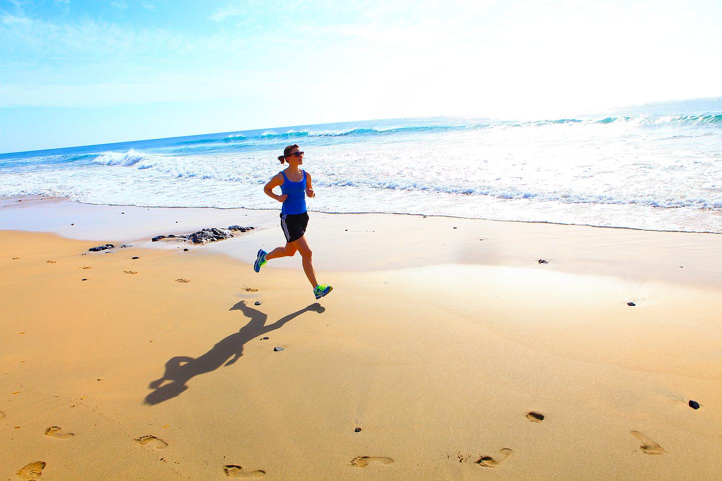 Eine junge, sportliche Frau, die am Strand entlangjoggt 