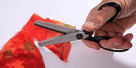 Roter Vliesstoff der von Schere gerade zerschnitten wird