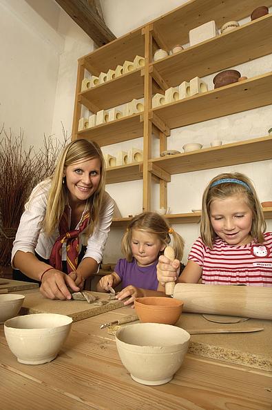 Angestellte und zwei Kinder beim Töpfern in der Töpferei von Schlosshof