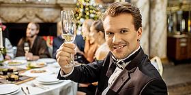 hübscher lächeldner Mann hebt Glas in Kamera