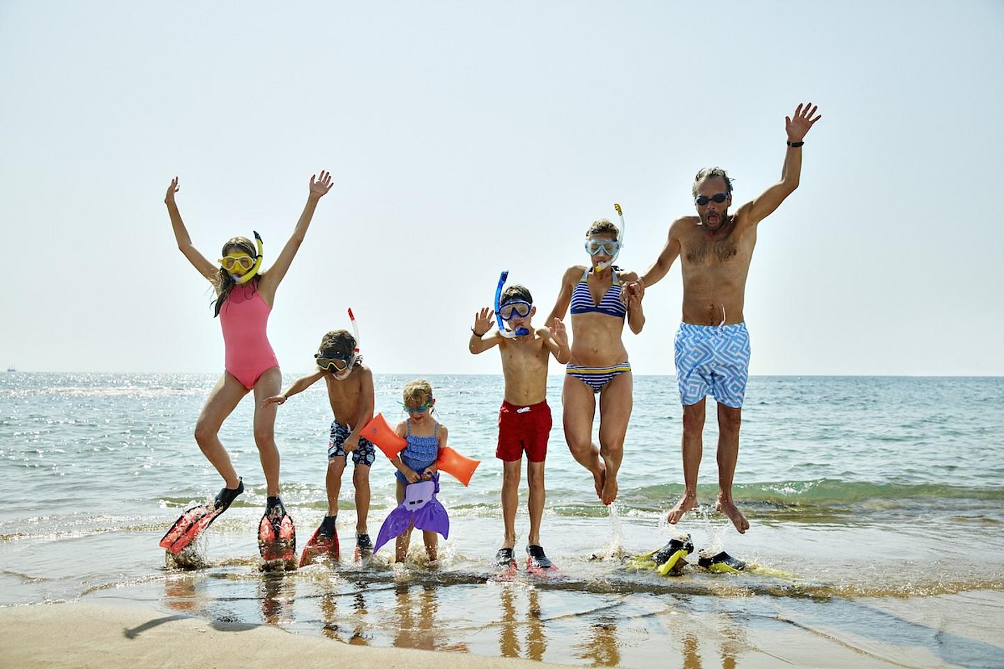 Familie mit 3 Kindern mit Flossen im Meer