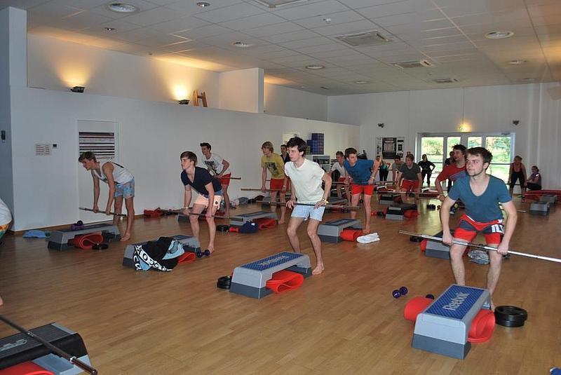 Schüler beim Fintesstraining mit Hantelstangen. 