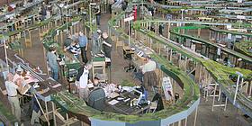 Modellbau Messe Ein riesige Modelleisenbahn wurde von mehreren Menschen in einer Halle aufgebaut.